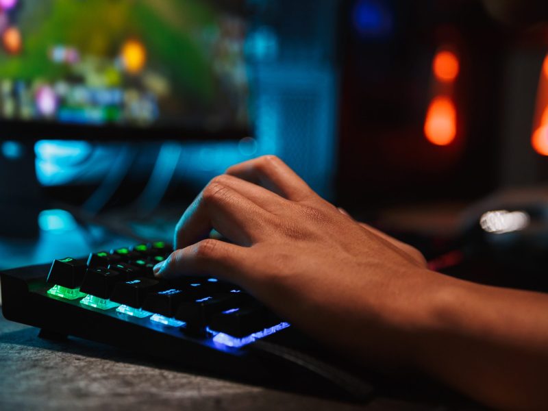 Man playing multiplayer games with keyboard in illuminated living room indoors.